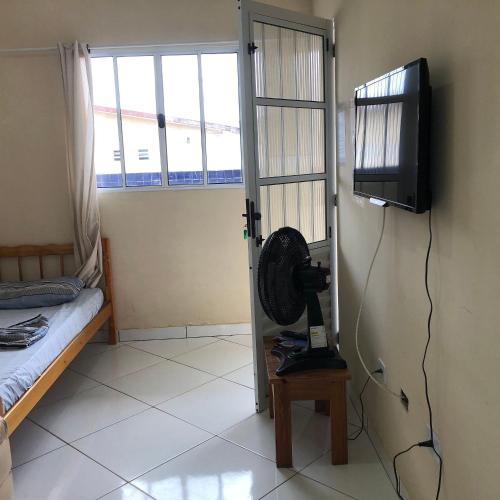 a room with a fan and a television on a wall at Pousada do Bene - Aluguel Casa in Guarujá