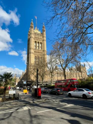 a large building with a tower with cars on a street at Elegant and Modern 3-Bedroom Victorian House in Westminster, London in London