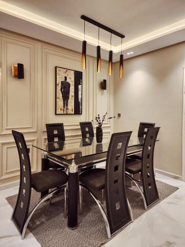a dining room with a glass table and black chairs at appartement de luxe réservée aux familles in Meknès