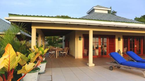 a house with a patio with blue chairs and a table at Caribbean Villa with pool and views in Port Elizabeth
