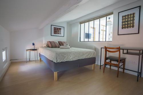 une chambre avec un lit et une chaise dedans dans l'établissement Le nid de la rue Mailly, à Perpignan