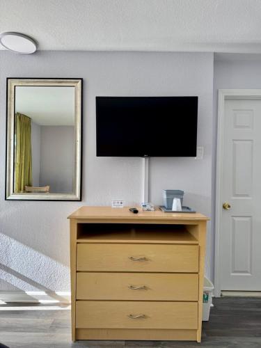 a tv on a wall with a dresser with a dresserngthngthngth at Chisholm's Motor Inn in Saugus