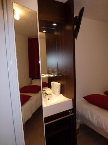 a bathroom with a sink and a mirror with two beds at Hotel Primo Colmar Centre in Colmar