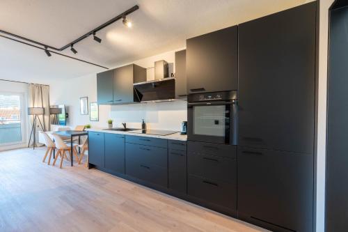 a kitchen with black cabinets and a table in it at Malu Rooms - im Zentrum, Kostenloser Parkplatz, Balkon, Netflix, 24h Checkin in Ludwigsburg