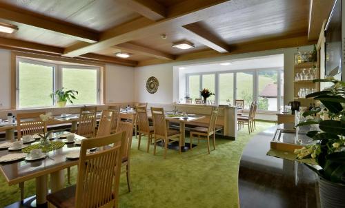 un restaurante con mesas y sillas de madera y ventanas en Hotel Garni Tirol, en Walchsee