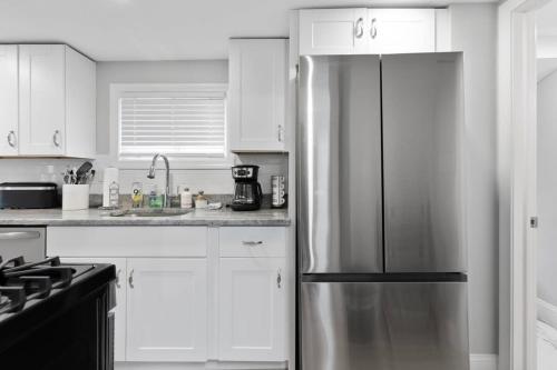 a kitchen with a stainless steel refrigerator and white cabinets at Newly Renovated Beachside Bliss Steps to Sand in Salisbury