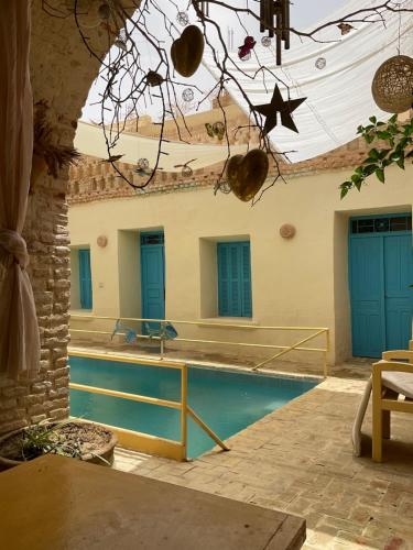 a swimming pool in a house with blue doors at Dar Amina in Tozeur