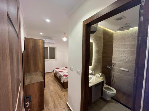 a bathroom with a sink and a toilet and a bed at Amoun sea view in Qaryat Shurūq