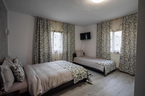 a bedroom with two beds and a window with curtains at Pensiunea Nituca in Moisei