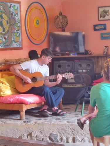 a man playing a guitar in a living room at Black Mamba in Paul