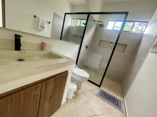 a bathroom with a toilet and a glass shower at Casa Campestre San Jerónimo in Tocaima