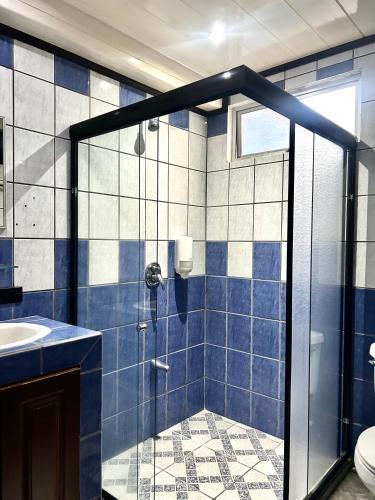 a blue tiled bathroom with a shower and a sink at Hotel Arenal Rabfer in Fortuna