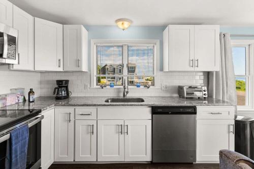a kitchen with white cabinets and a sink at Snug Seaside Views From Couch Walk to Beach in Rye