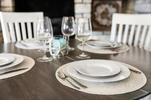 a wooden table with plates and wine glasses on it at Snug Seaside Views From Couch Walk to Beach in Rye