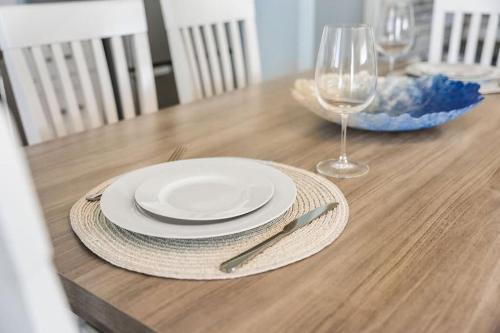 a wooden table with a plate and a glass of wine at Snug Seaside Views From Couch Walk to Beach in Rye