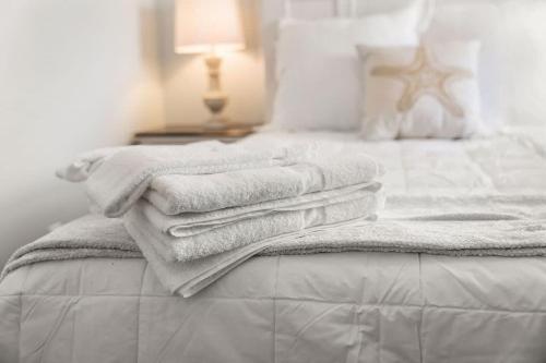 a pile of towels sitting on top of a bed at Snug Seaside Views From Couch Walk to Beach in Rye