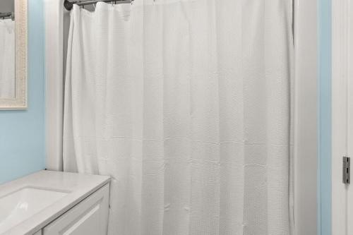 a bathroom with a white shower curtain and a sink at Snug Seaside Views From Couch Walk to Beach in Rye