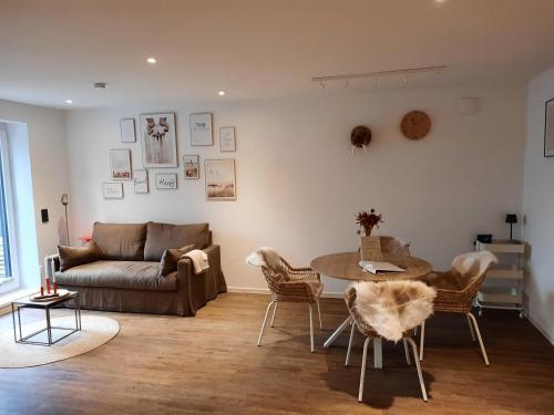 a living room with a couch and a table and chairs at Lachmoewe-by-DeJu in Norderney
