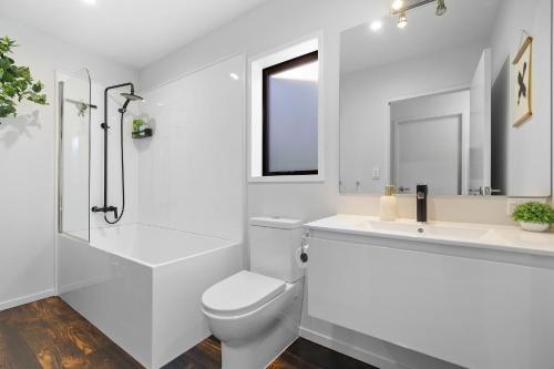 a white bathroom with a toilet and a sink at Lake View Viscount in Queenstown