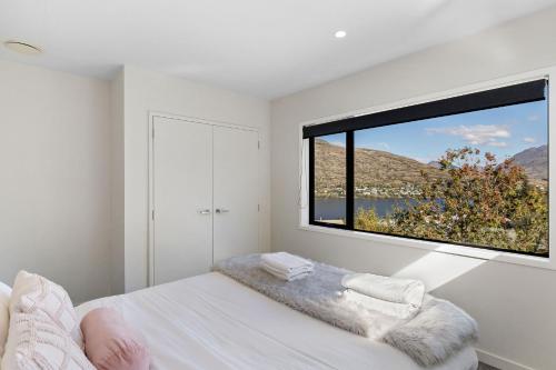 a bedroom with a bed and a large window at Lake View Viscount in Queenstown