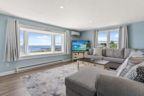 a living room with a couch and a tv and windows at The Sunrise Deck Ocean Views Private Deck in Rye