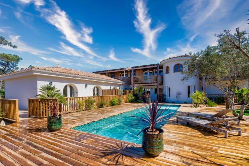une maison avec une piscine et une terrasse en bois dans l'établissement Les Villas de Julie au Domaine des Muses, à Lacanau