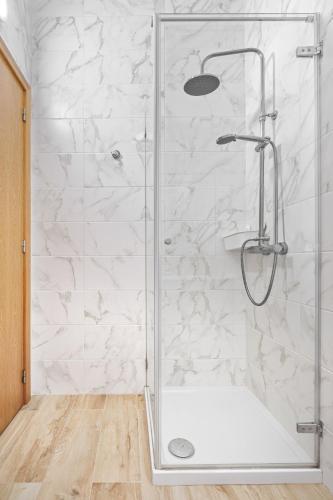 a shower in a bathroom with white marble walls at Sunny House with Patio, Walk to Attractions in Vila Nova de Gaia