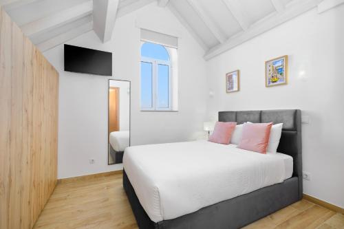 una camera da letto con un letto bianco e cuscini rosa di Sunny House with Patio, Walk to Attractions a Vila Nova de Gaia
