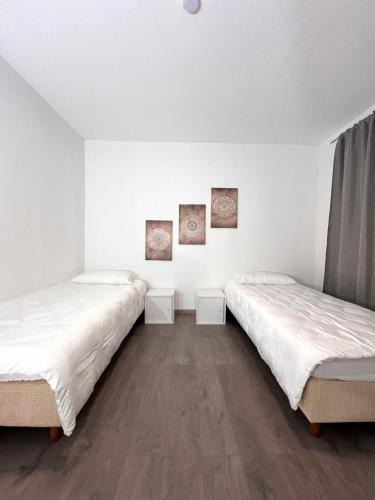 two beds in a room with white walls and wooden floors at Modern classic apartment in Lauenau