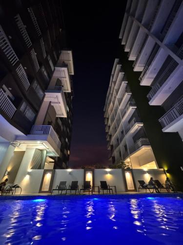 a hotel swimming pool at night with two tall buildings at Cozy Staycation Studio in Iloilo by Alfasuite Iloilo in Iloilo City