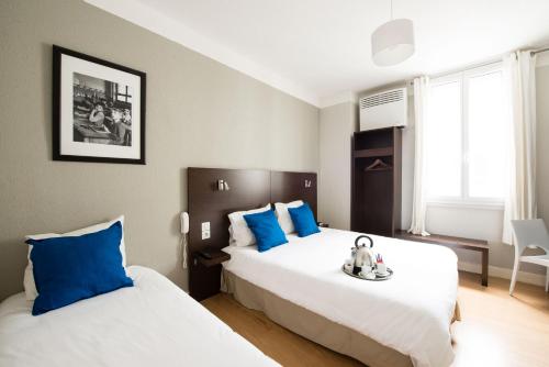 a bedroom with two beds with blue pillows at H&ocirc;tel Atrium Mondial in Lourdes
