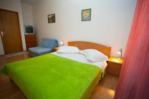 a bedroom with a green bed and a blue chair at Studio Apartment Mrnjica in Brela