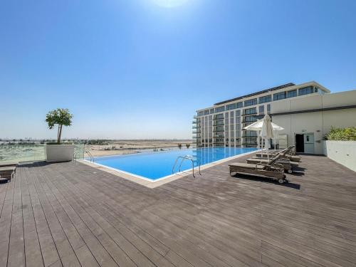 a building with a swimming pool next to a building at Free housekeeping visits during your stay - StayShort - Bright & Elegant 2BR in Creek Harbour in Dubai