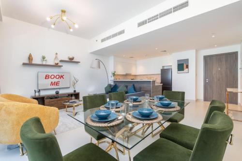 a living room with a glass table and green chairs at Free housekeeping visits during your stay - StayShort - Bright & Elegant 2BR in Creek Harbour in Dubai