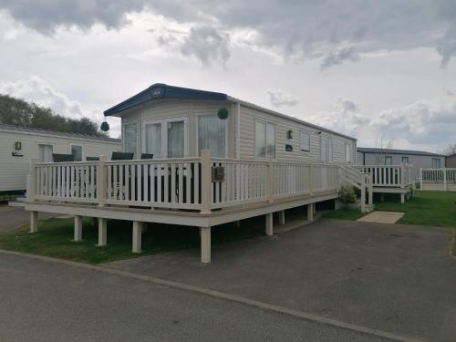 a large white mobile home with a large deck at Luxury Caravan with Hot tub on Tattershall lakes in Lincoln