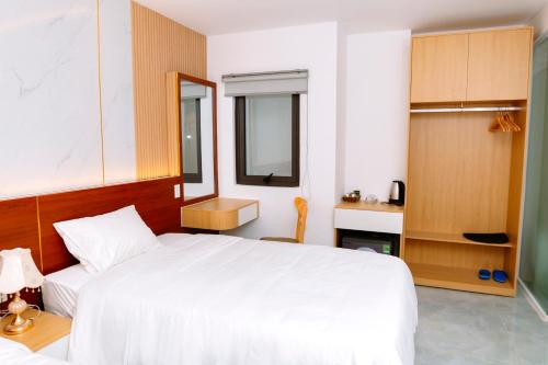 a bedroom with a large white bed and a mirror at Khách sạn Ngọc Khanh in Phan Rang