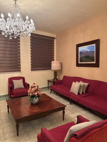 a living room with red couches and a chandelier at Departamento vintage in Papantla de Olarte