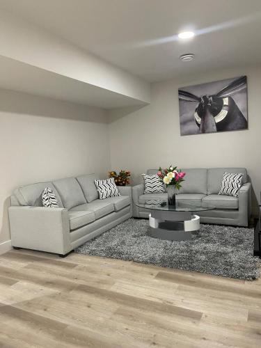 a living room with two couches and a table at Modern suite in basement Upland in Edmonton