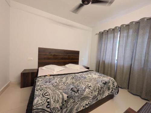a bedroom with a bed and a window with curtains at Just Us in McLeod Ganj