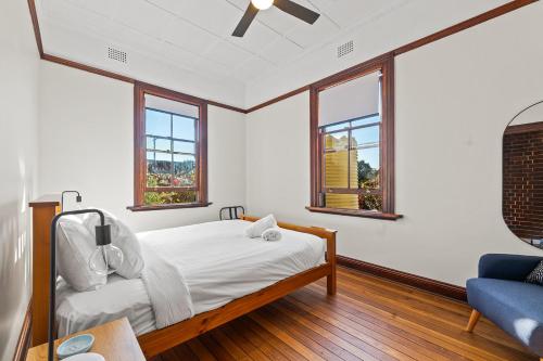 a bedroom with a bed and a couch and windows at On Chapel St, The Royal Hotel Dalton in Dalton