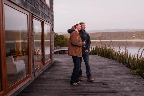 two men standing on a boardwalk next to a building at Palafito Cucao in Cucao