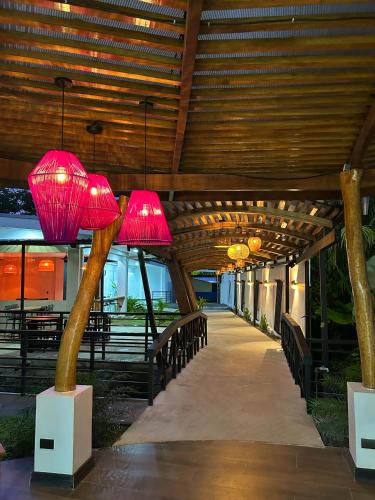 a covered walkway with two pink lamps on top at Villa del Mar Hotel Boutique in Cahuita