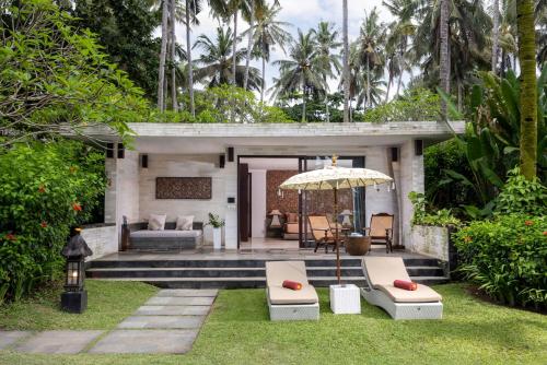 a patio with a couch and an umbrella at Kelapa Retreat & Spa in Pulukan
