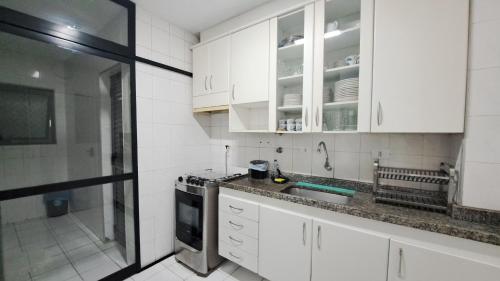 a kitchen with white cabinets and a sink at Pitangueiras Pé na Areia in Guarujá