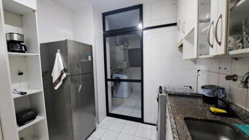a small kitchen with a refrigerator and a sink at Pitangueiras Pé na Areia in Guarujá