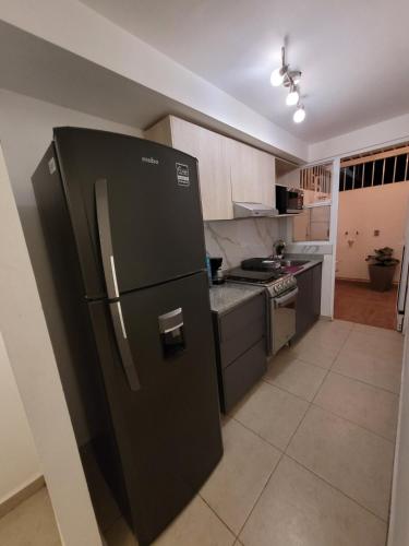 a kitchen with a black refrigerator and a stove at Casa Privada El Marqués Qro in Querétaro