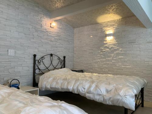 a bedroom with two beds and a brick wall at Kakureyado Fujikawaguchiko in Fujikawaguchiko