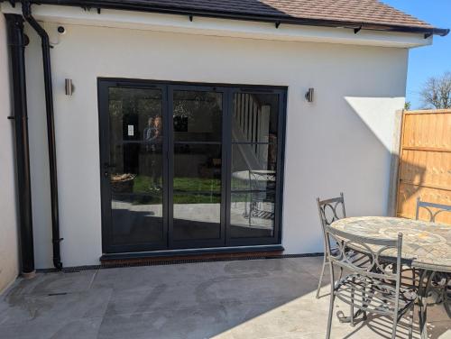 a sliding glass door on a patio with a table at Ox Lane Annexe - Harpenden in Harpenden
