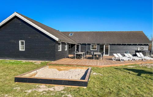 a house with a deck with chairs and a patio at Stunning Home In Idestrup With Sauna in Marielyst