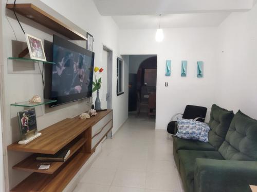 ein Wohnzimmer mit einem grünen Sofa und einem Flachbildfernseher in der Unterkunft Sol e mar in Fortaleza